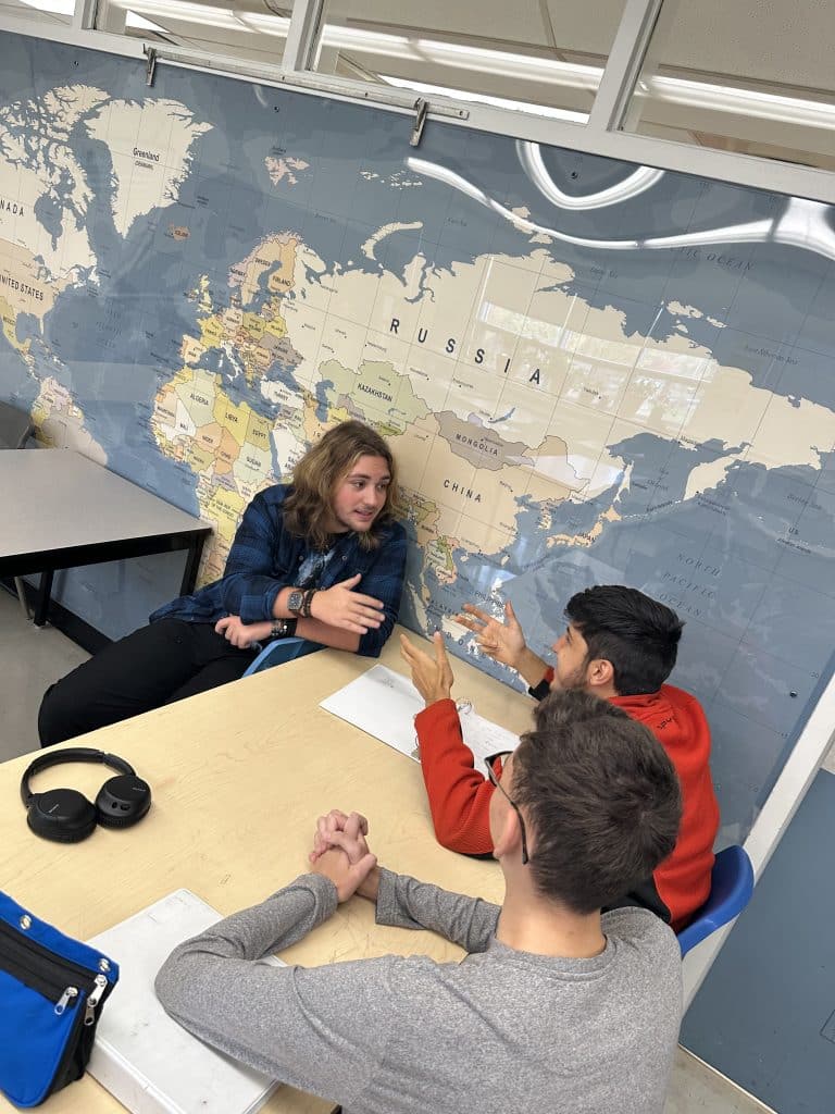 Students discussing in front of mural of the world